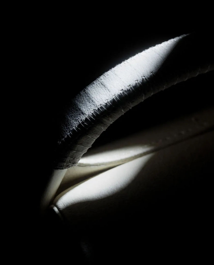 A hand wrapped around a stitched leather grip, knuckles pale in a narrow beam of light, the rest of the frame falling to black