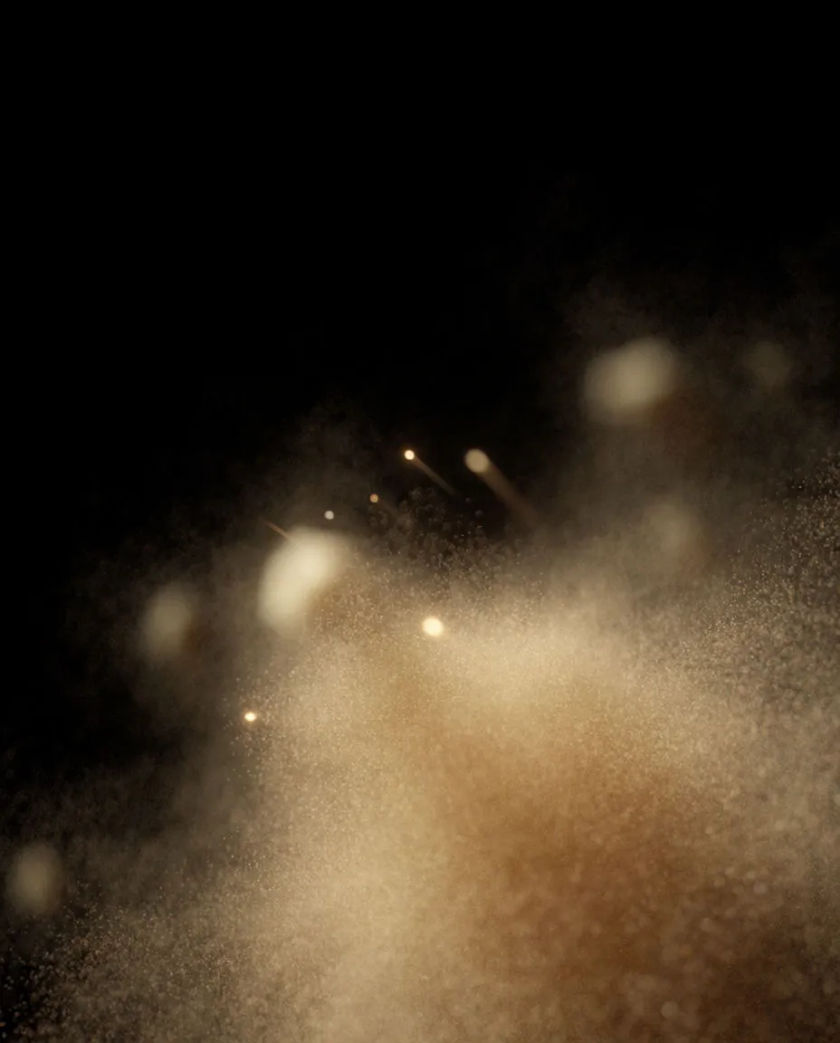 A cloud of fine golden specks drifting and glittering in the dark, a few brighter points trailing small streaks of light