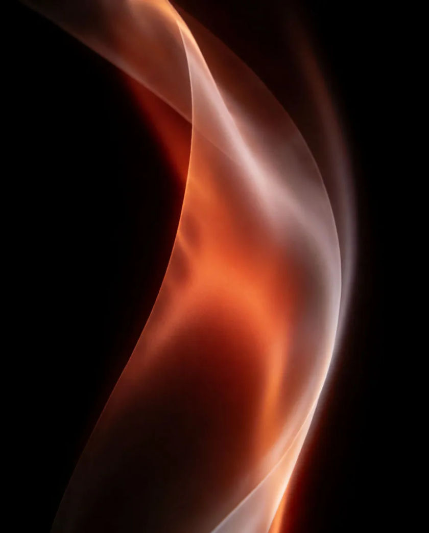 A long ribbon of satin light sweeping in a smooth arc across a pure black background, a soft glow trailing behind the curve