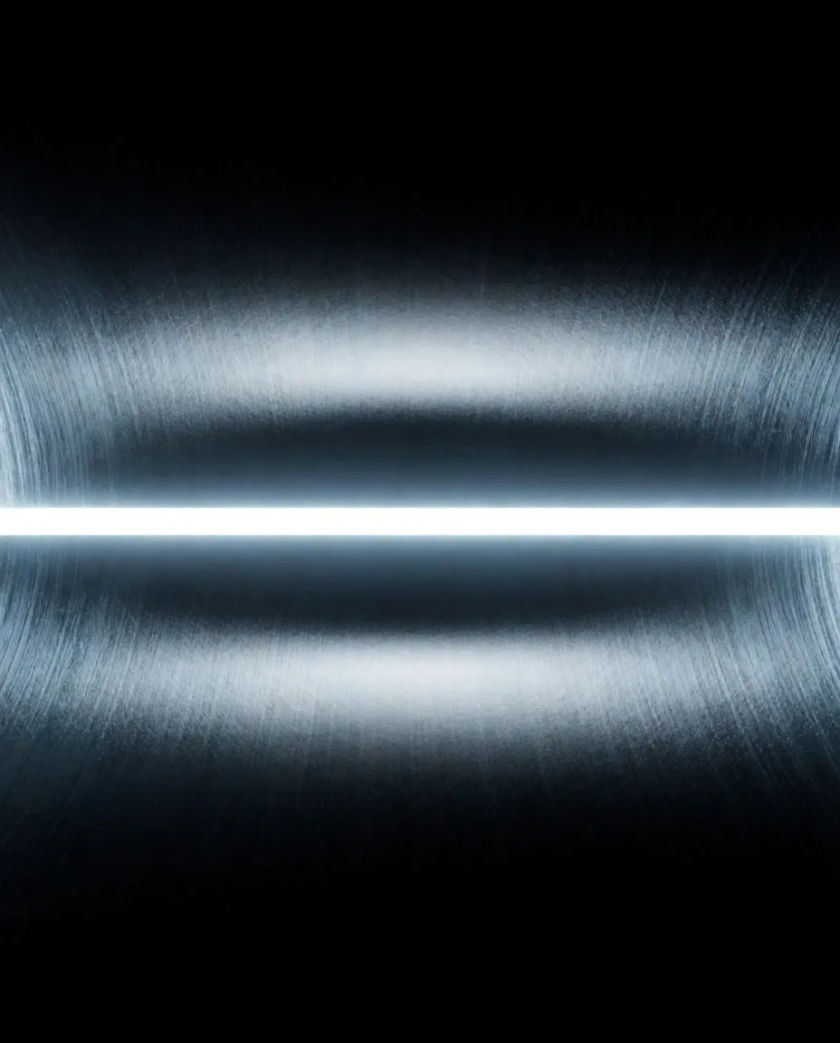 A narrow bar of white light stretching into a tunnel of fine streaks that curve toward a bright point, set against a black void