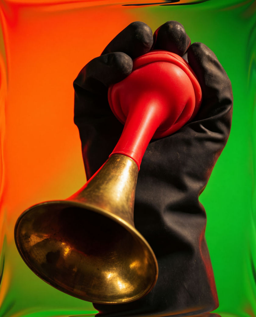 A rubber bulb horn squeezed flat in a fist against a hot clashing colour field, the frame smeared as if the picture itself is distorting
