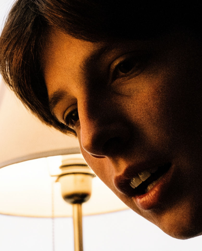 A half-turned face caught mid-question in hard side light, the background dropping to black