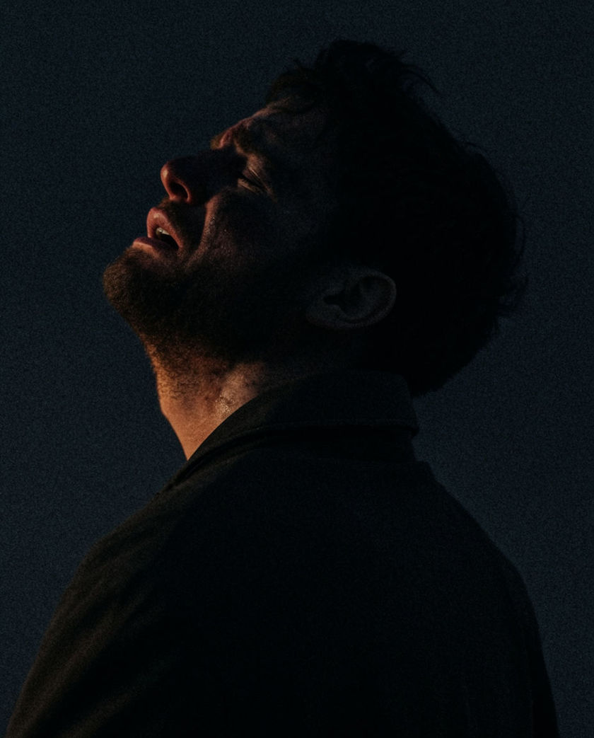 A 4:5 frame of a face turned hard away from the light, mouth wide open, everything but the throat falling into shadow