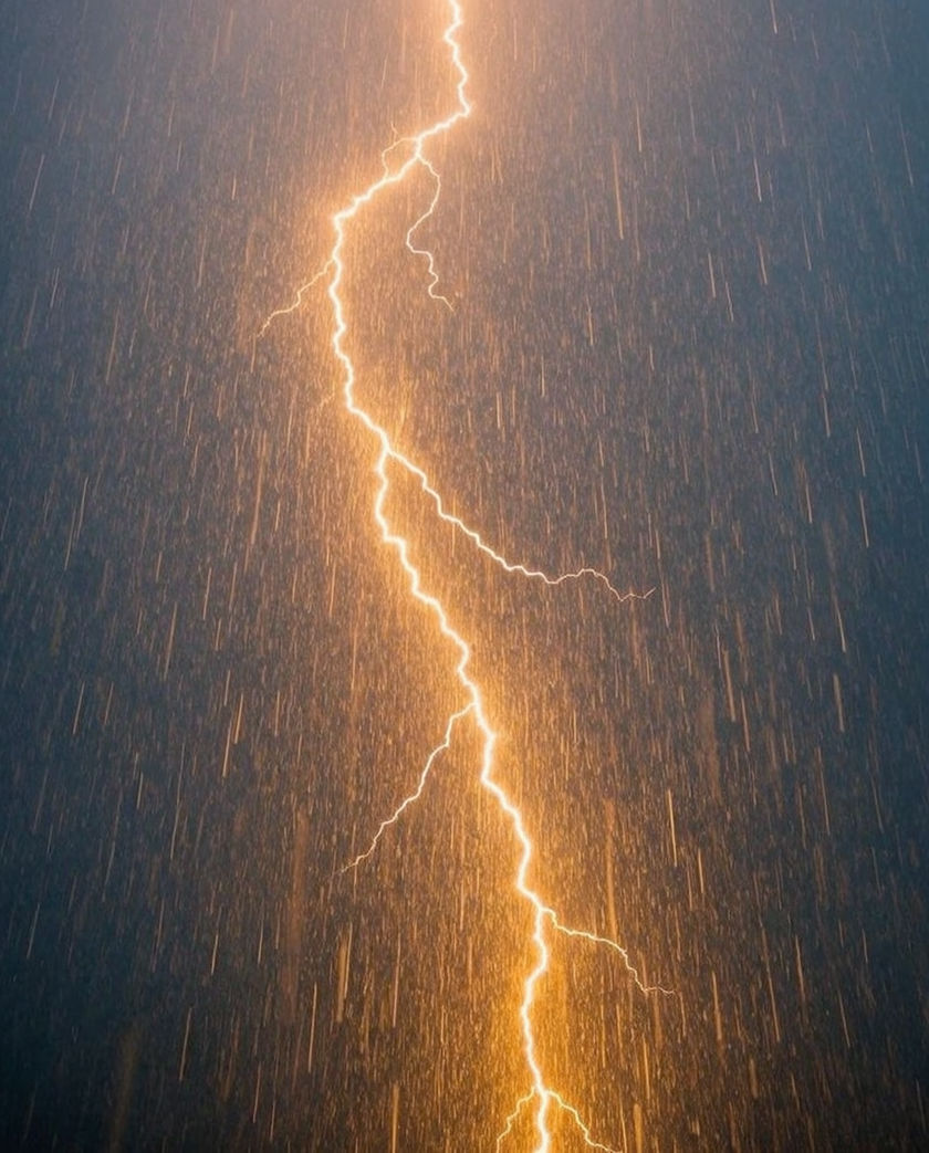 A fork of lightning over a dark ridge, rain sheeting across the middle distance