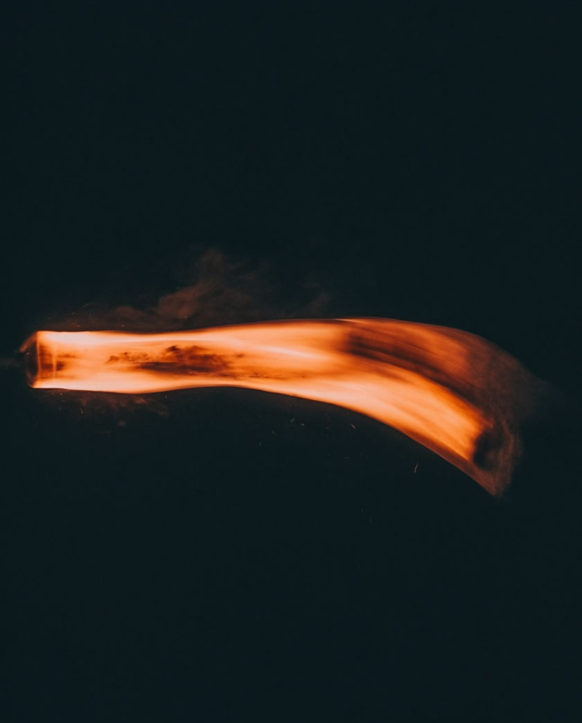 A streak of motion blur cutting diagonally across a dark ground, edges dissolving into grain