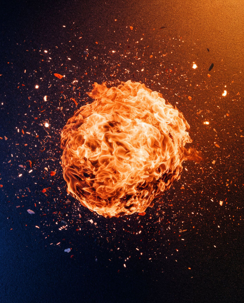 A ball of flame at a low three-quarter angle mid-launch, its warm light streaking forward against a dark ground