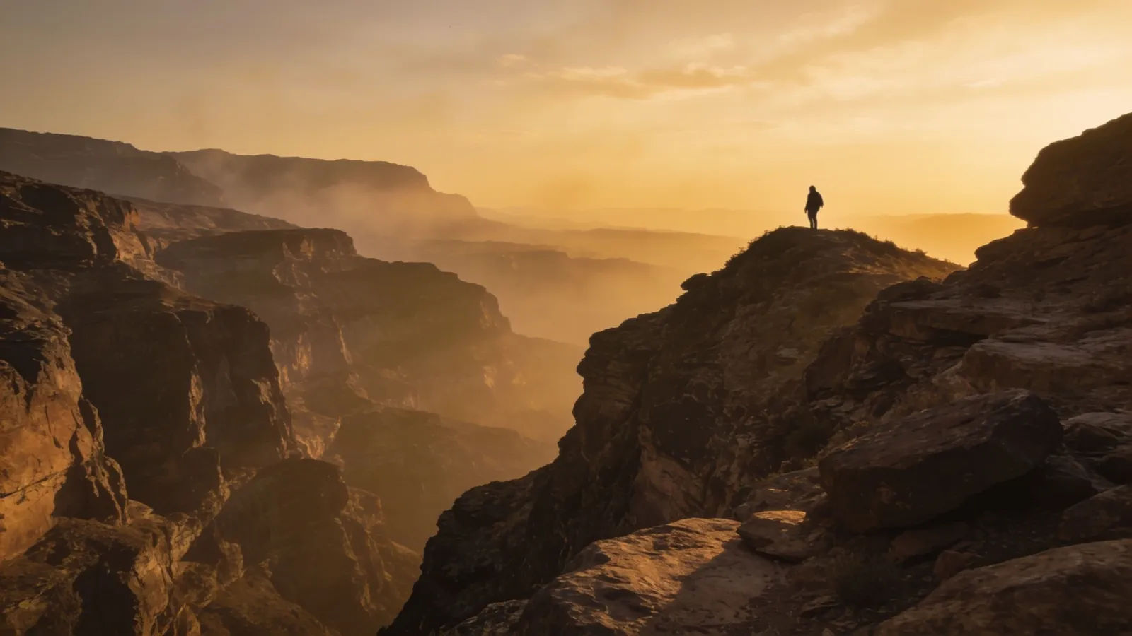 Vast canyon at dusk with distant climbing figure