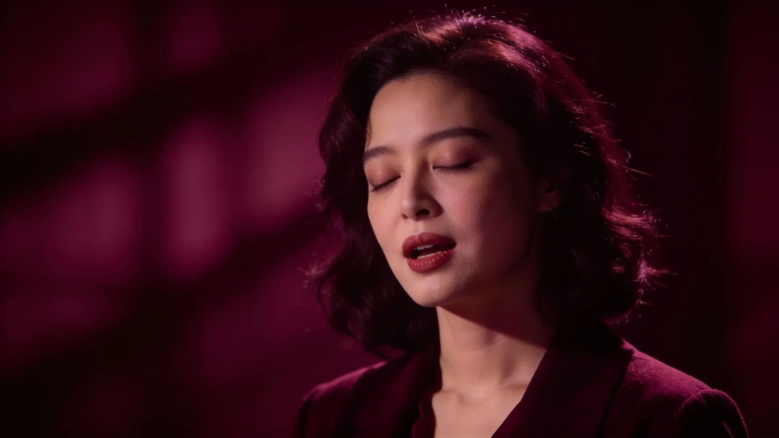 Expressive woman in velvety burgundy low-key cinematic portrait