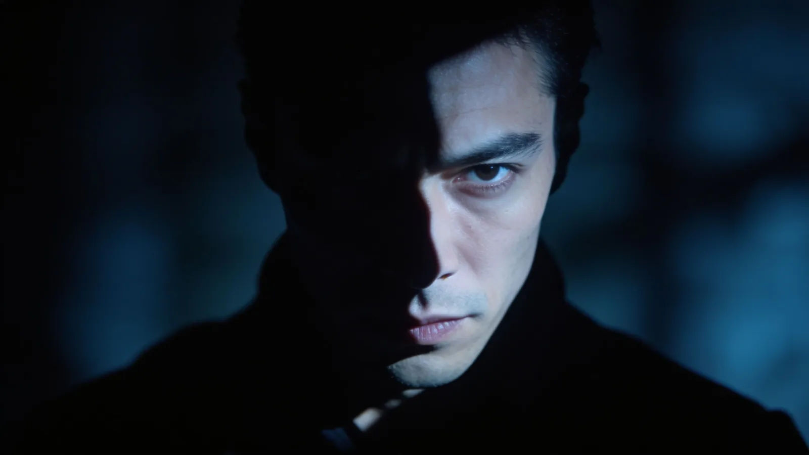 Shadowed menacing figure in steel-blue chiaroscuro portrait