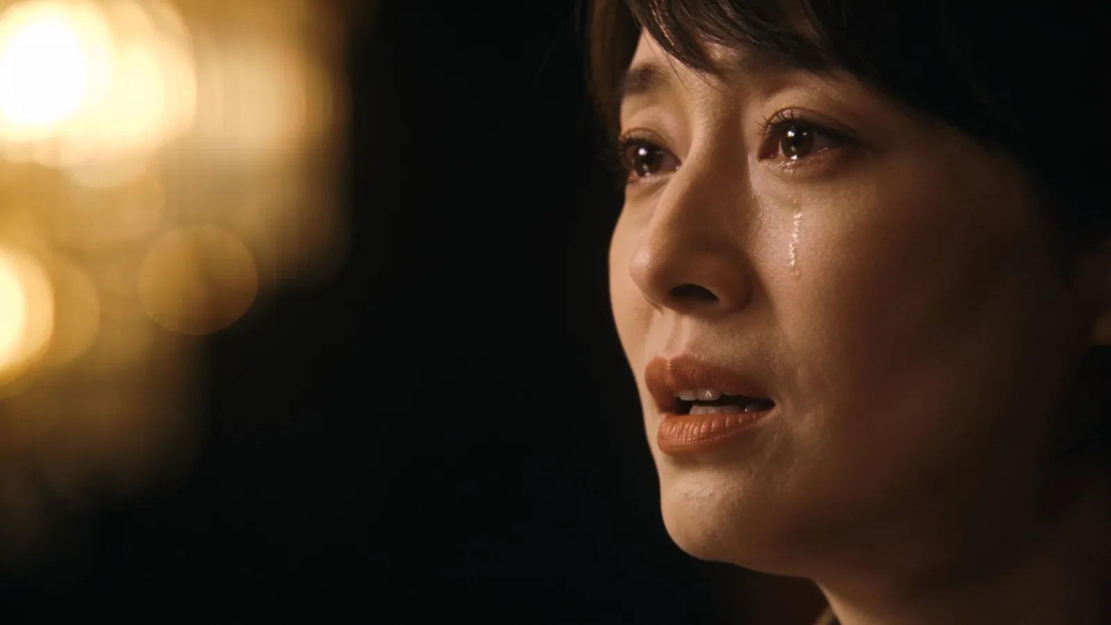 Grateful teary person mid-speech in warm spotlight