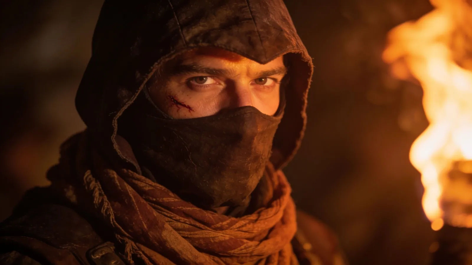 Masked hooded outlaw, firelit with a scar
