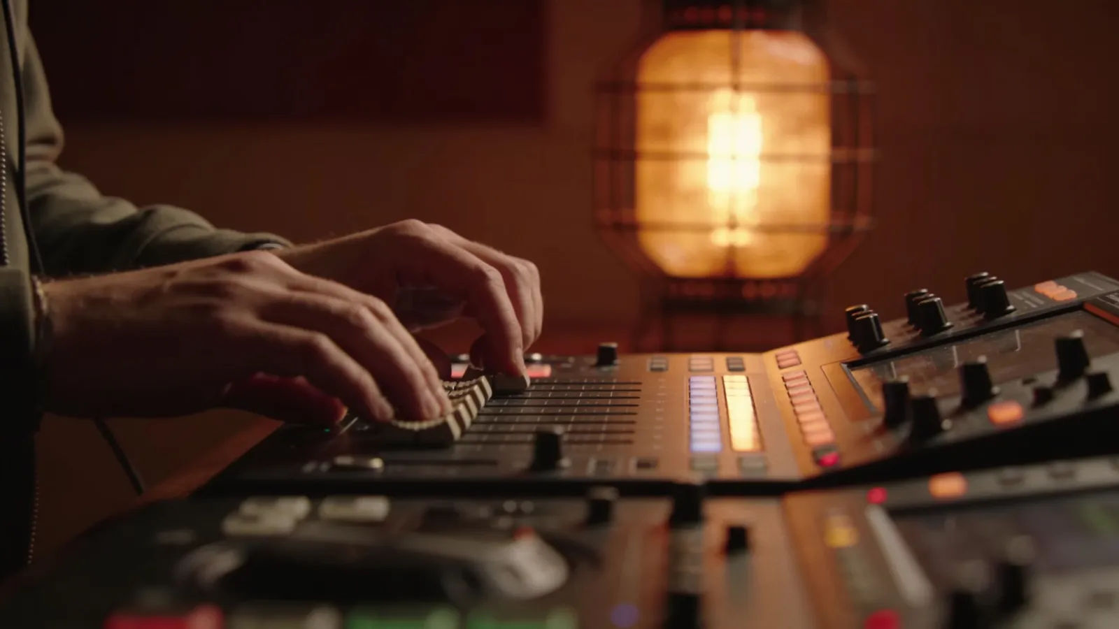 Hands at console with warm audio interface light