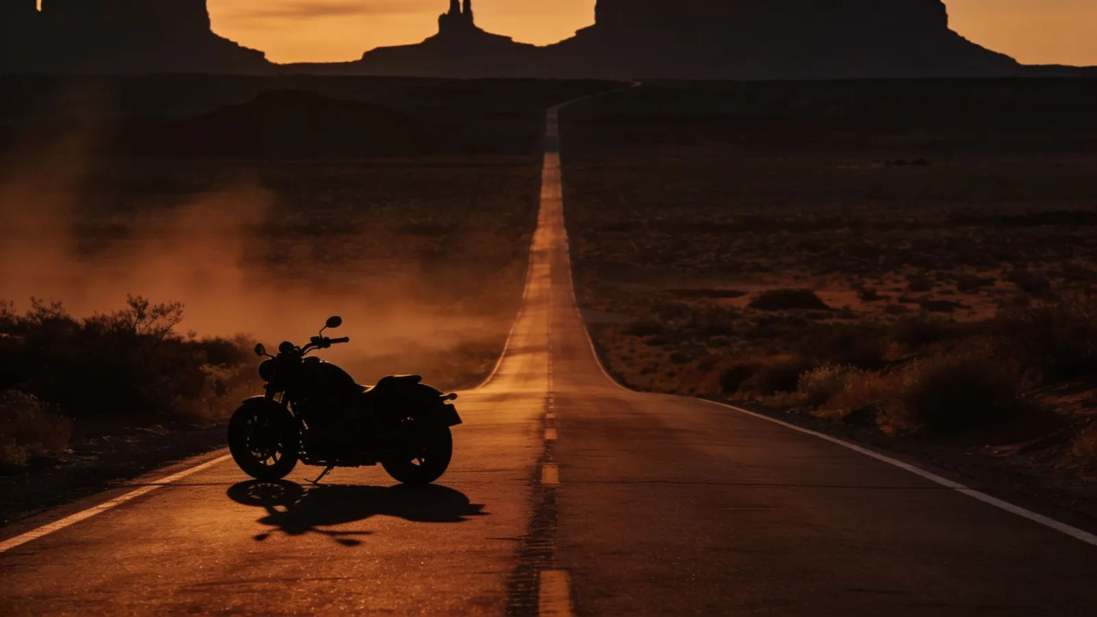 Lone motorcycle on open desert highway at dusk