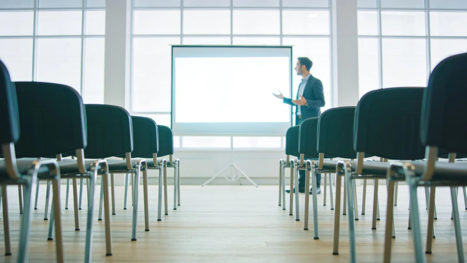 Bright startup pitch room with presenter and screen