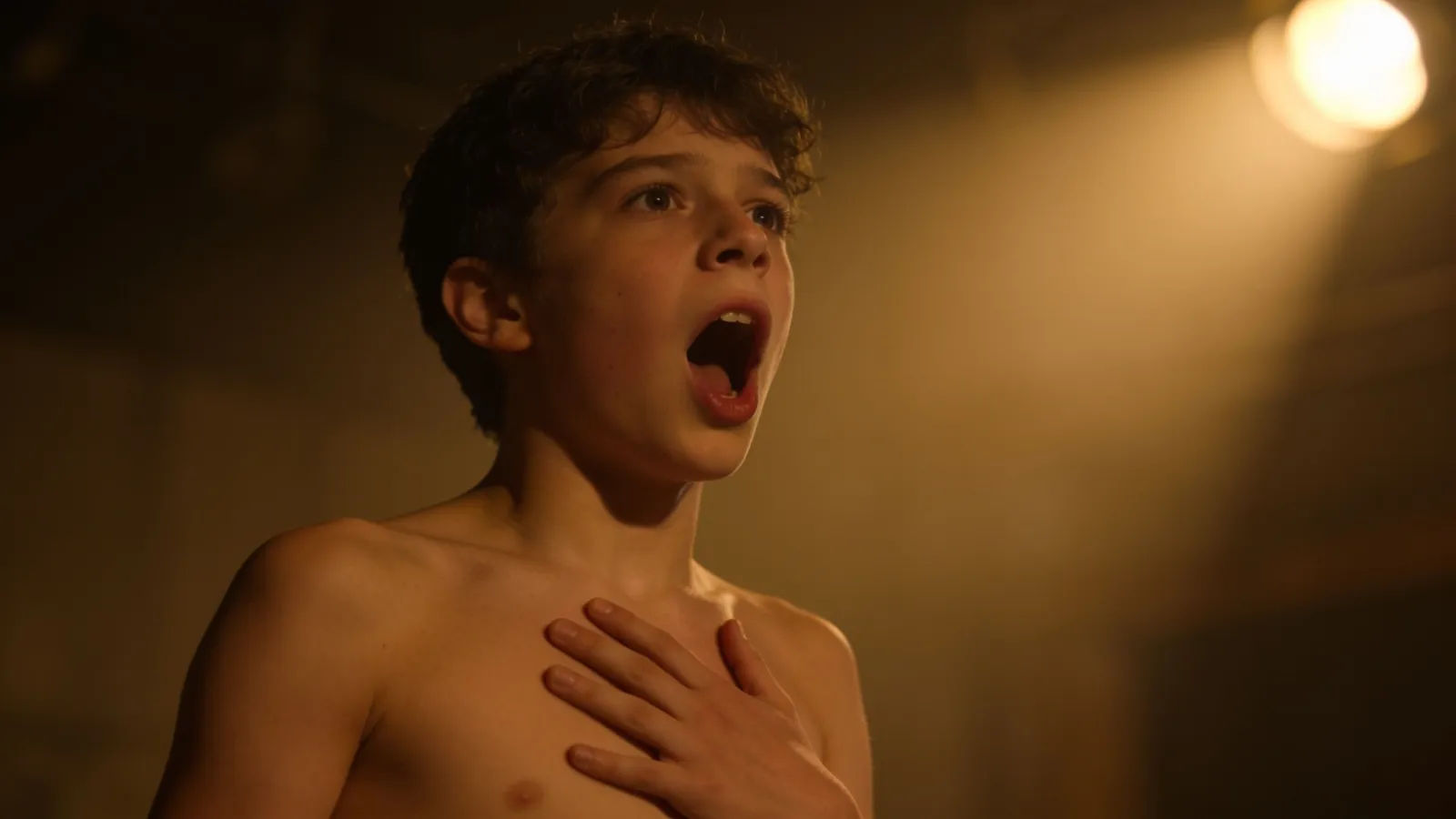 Theatrical performer mid-gasp, hand to chest, amber light