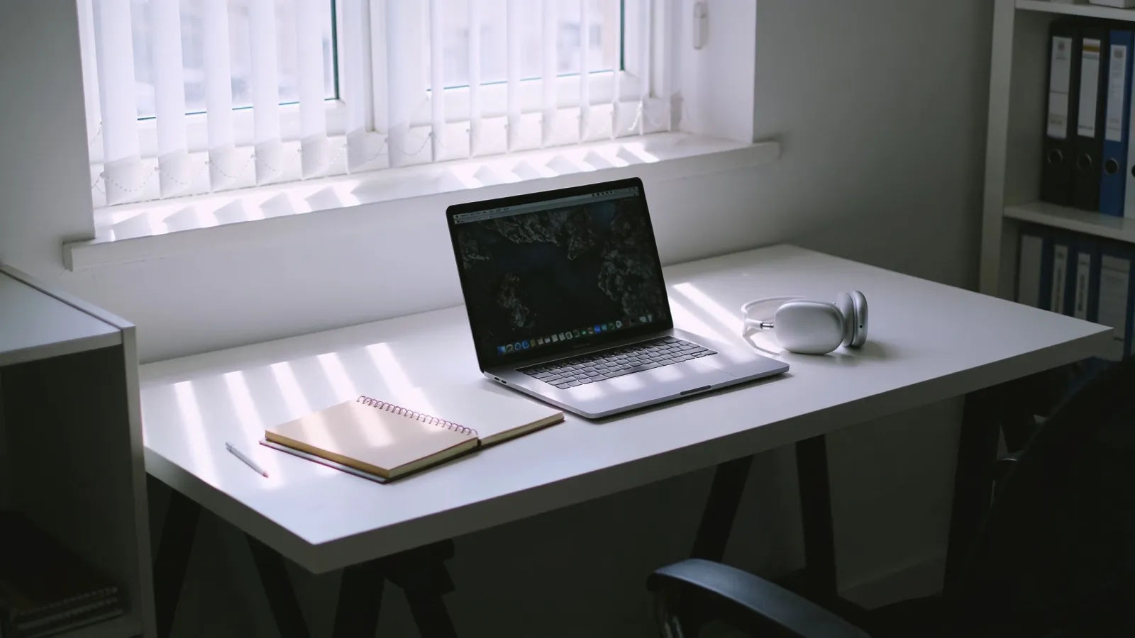 Modern home-study desk with glowing laptop and headphones
