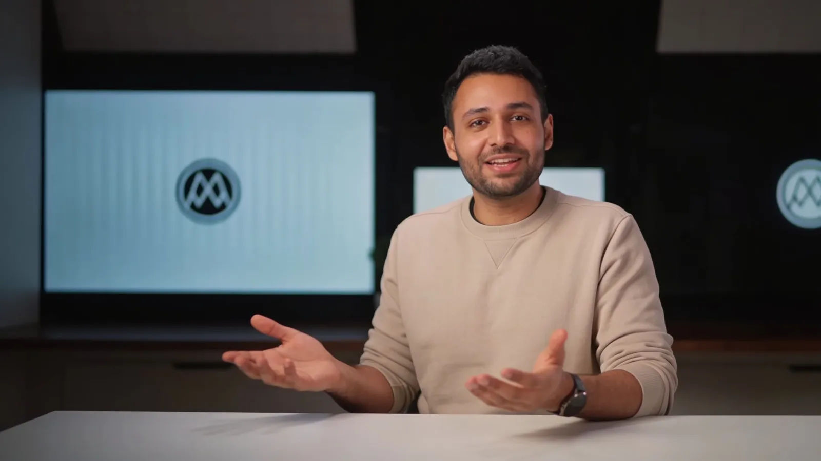 Warm presenter explaining at a clean desk