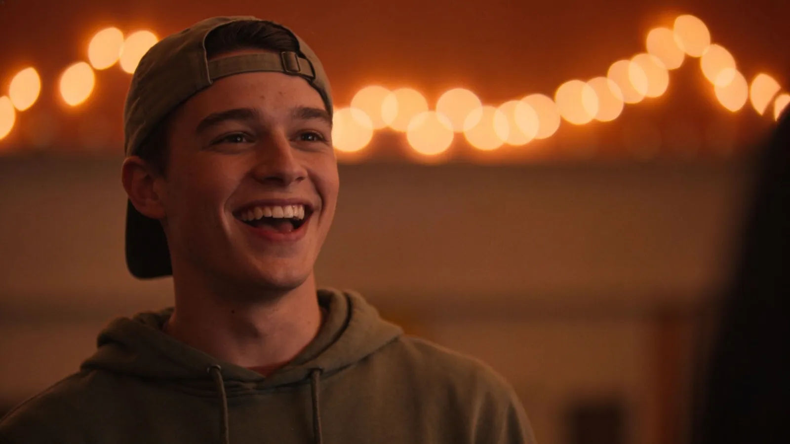 Energetic young college guy mid-laugh under party lights