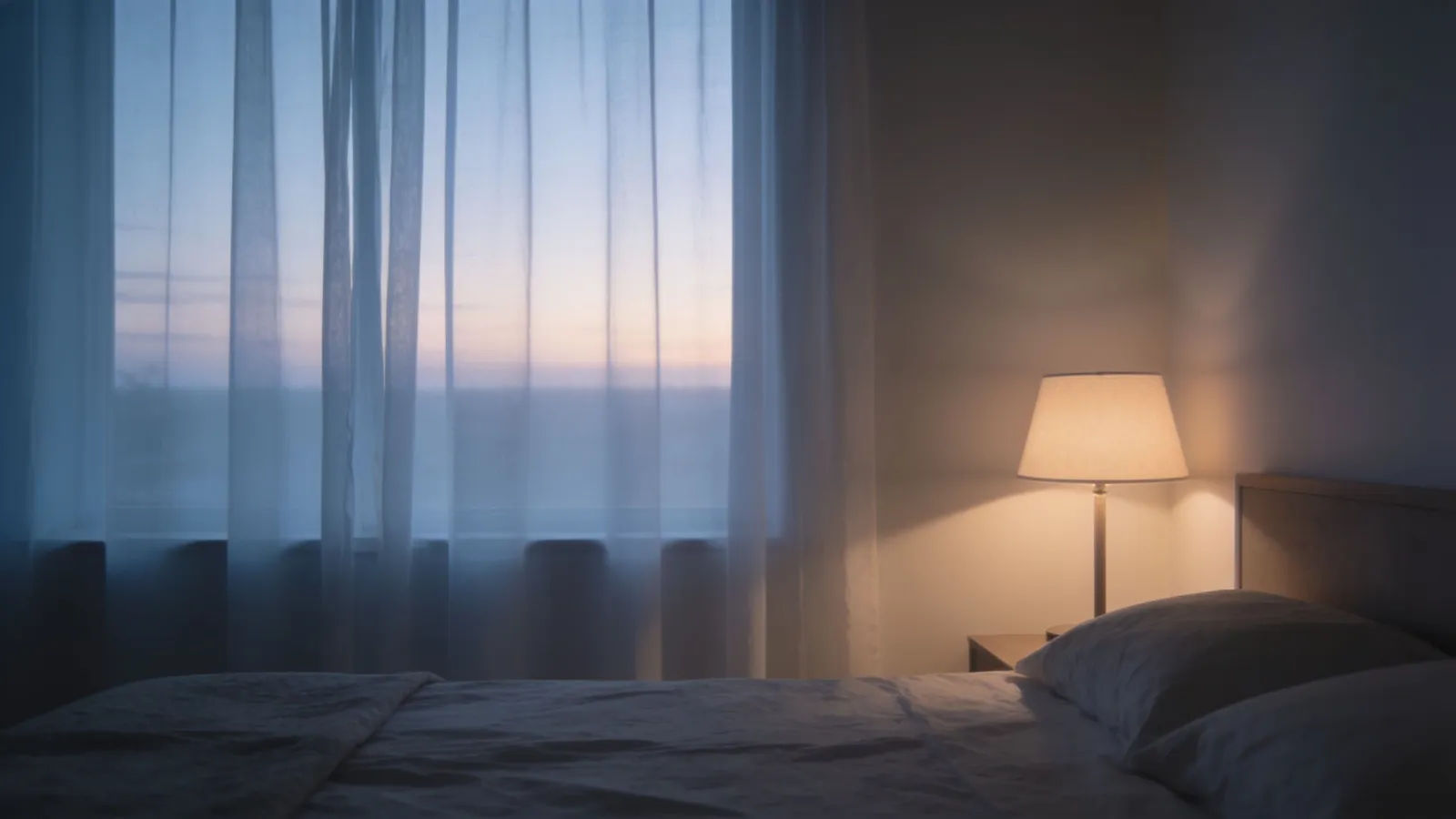 Quiet dawn bedroom with glowing reading lamp