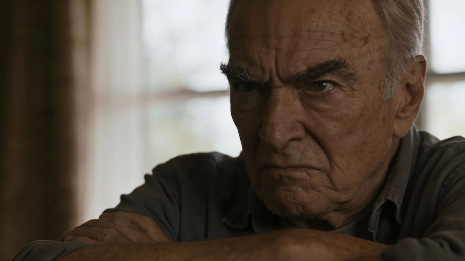Weathered scowling elderly man with crossed arms