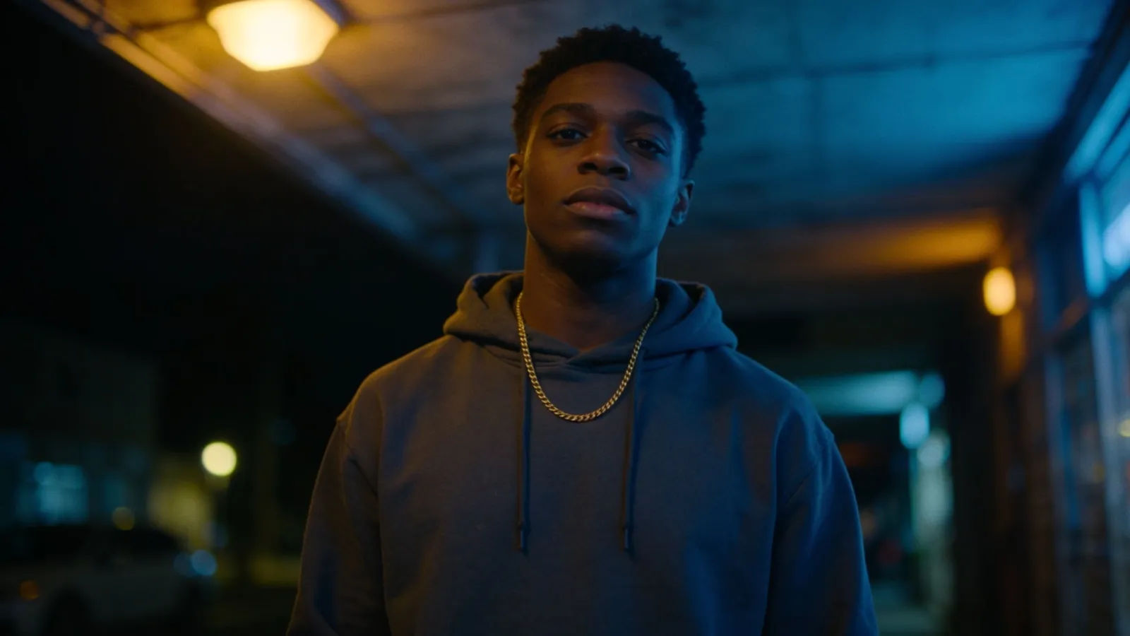 Confident young performer in hoodie under moody street light