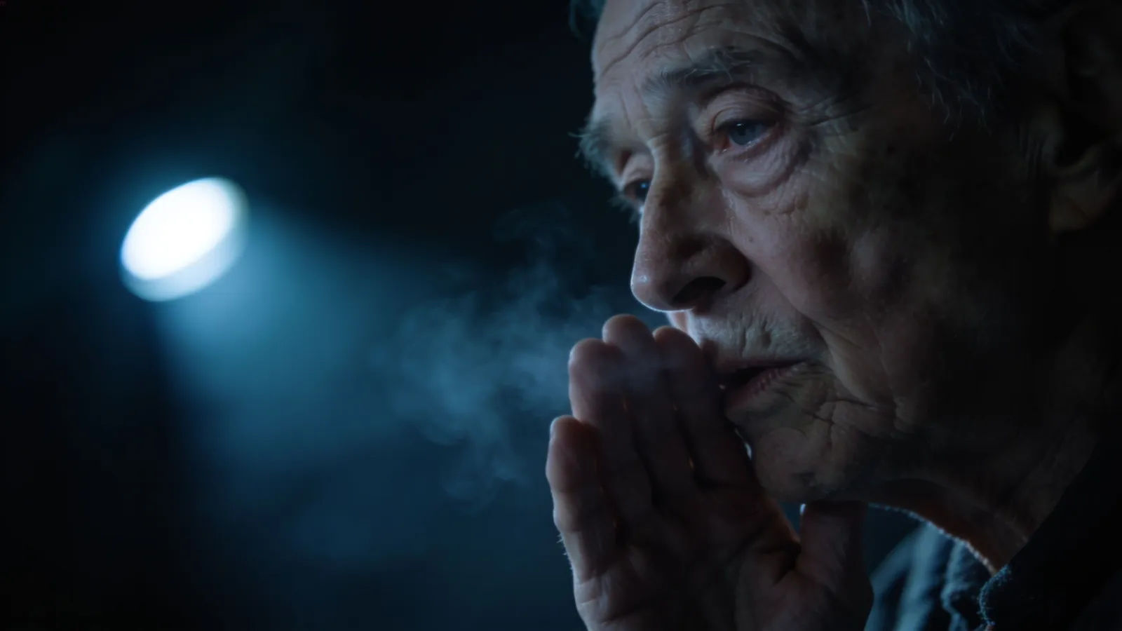 Frail worn elder mid-whisper in cold light