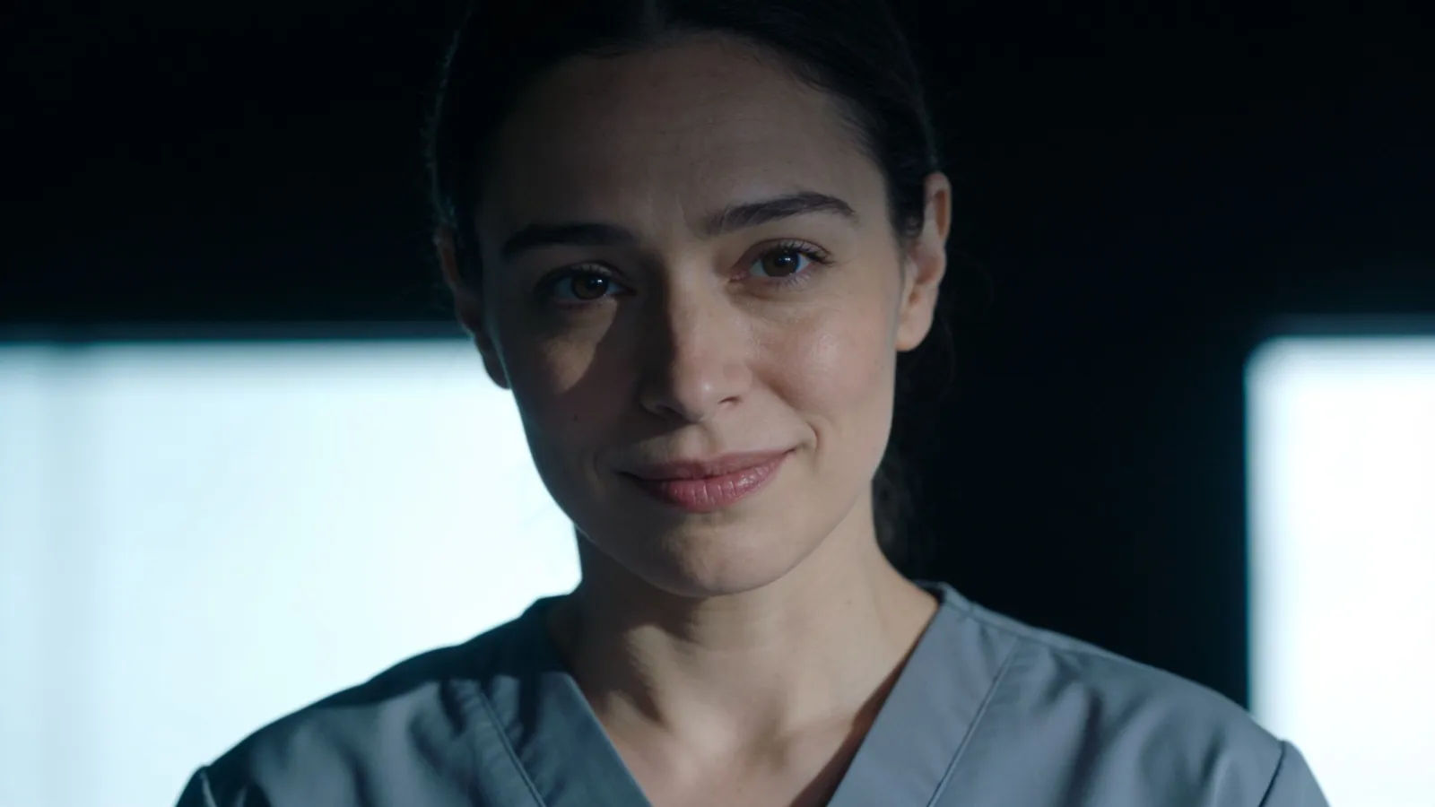 Calm caregiver in plain scrubs, reassuring expression