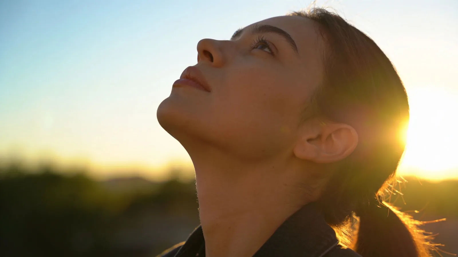 Confident person looking upward, radiant sunrise backlight