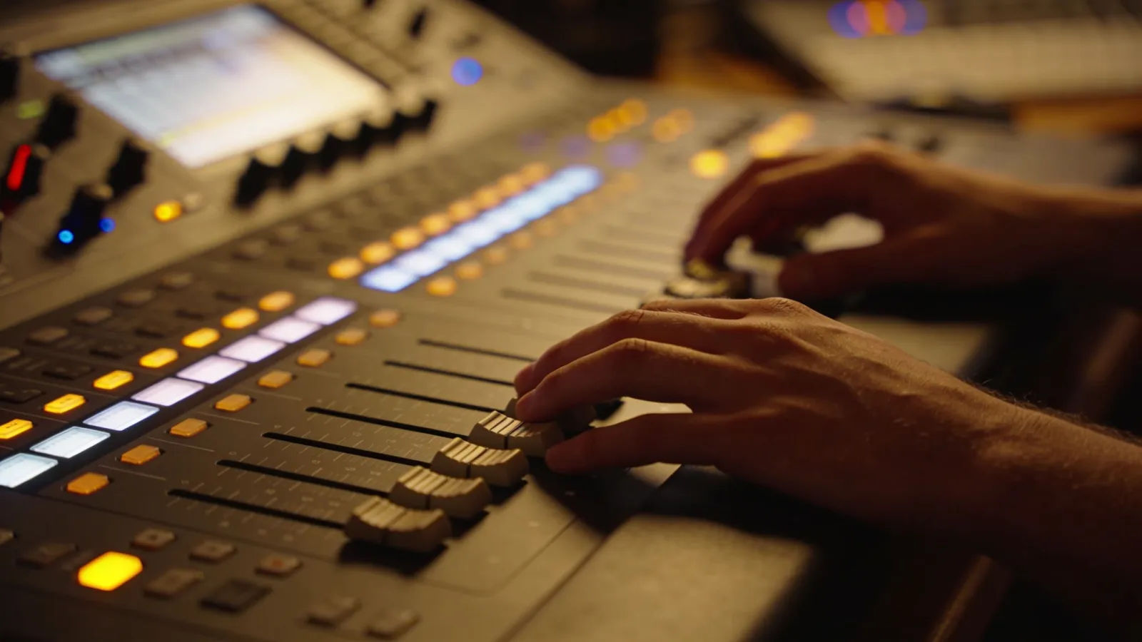 Hands resting on dim warm audio console