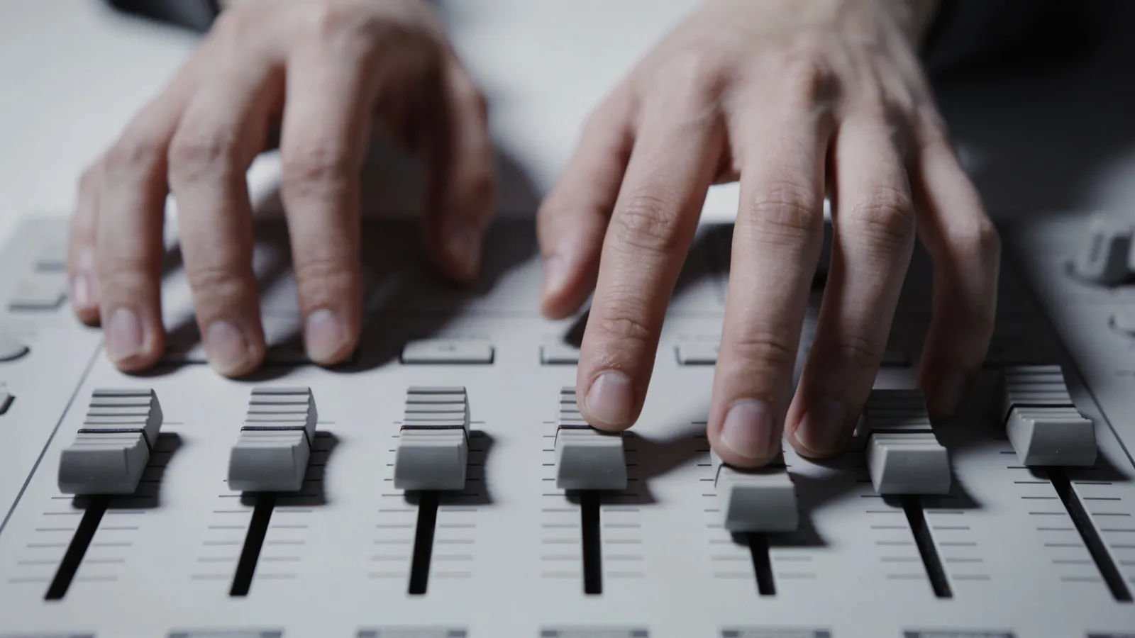Hands at a minimalist monochrome audio console