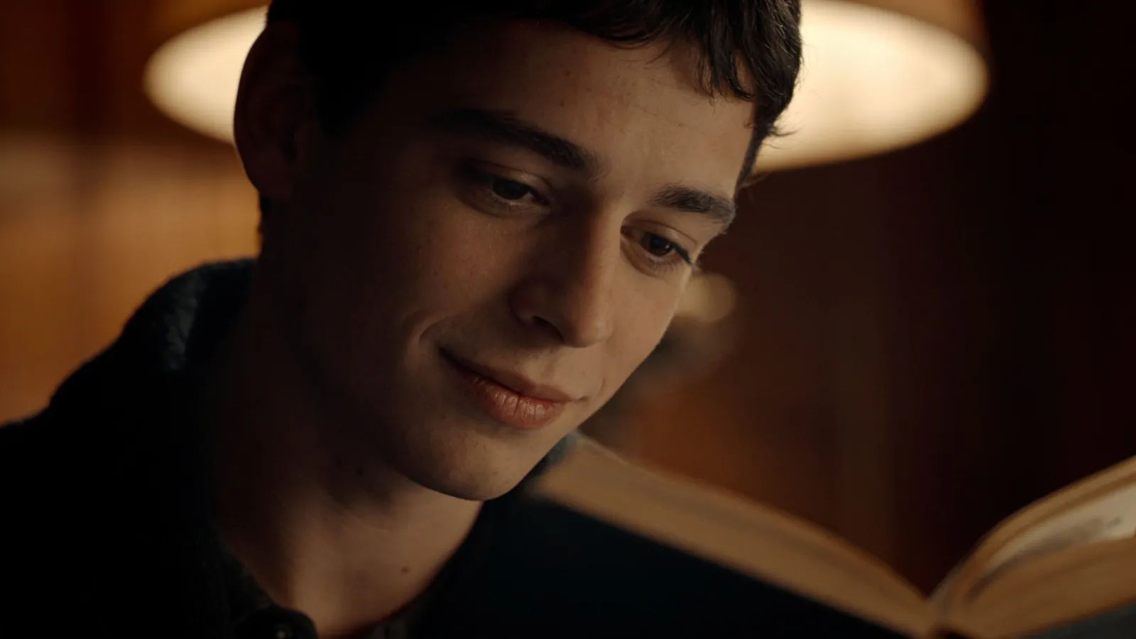 Warm storyteller mid-read, lamplit cinematic portrait