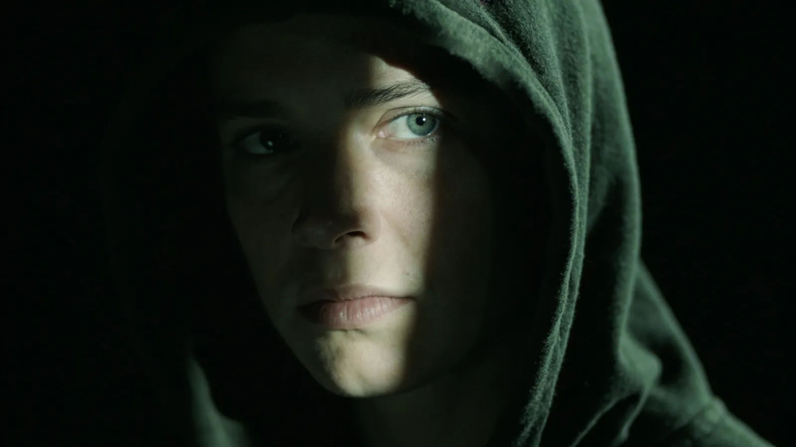 Shadowed hooded figure half-lit in pale sliver