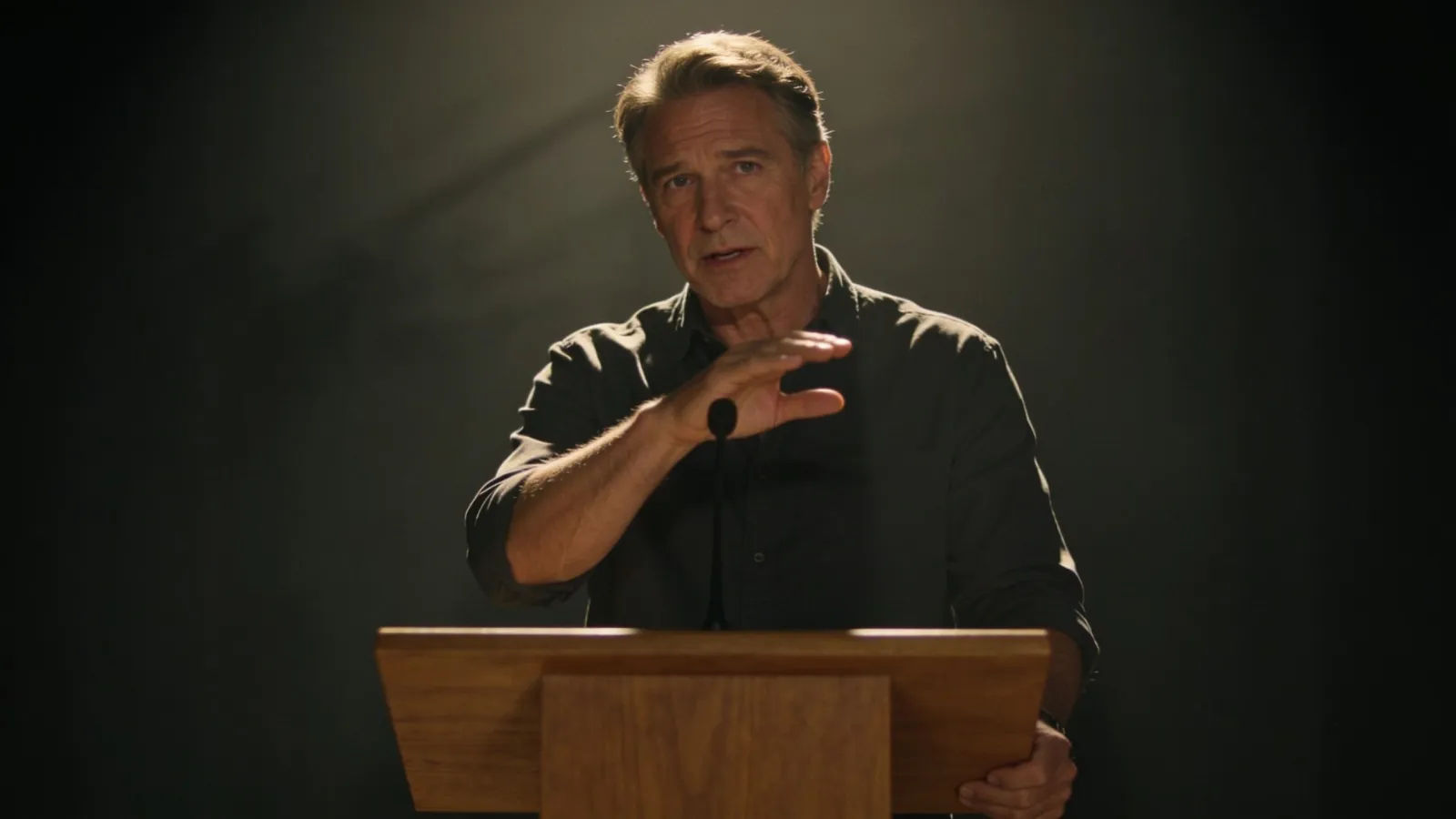Expressive speaker gesturing at a plain lectern