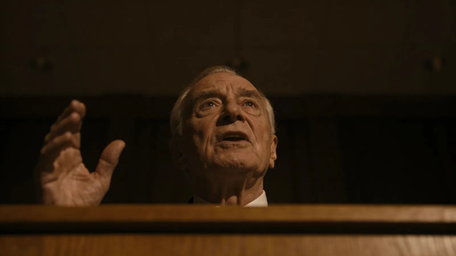 Dignified orator gesturing at a wooden lectern