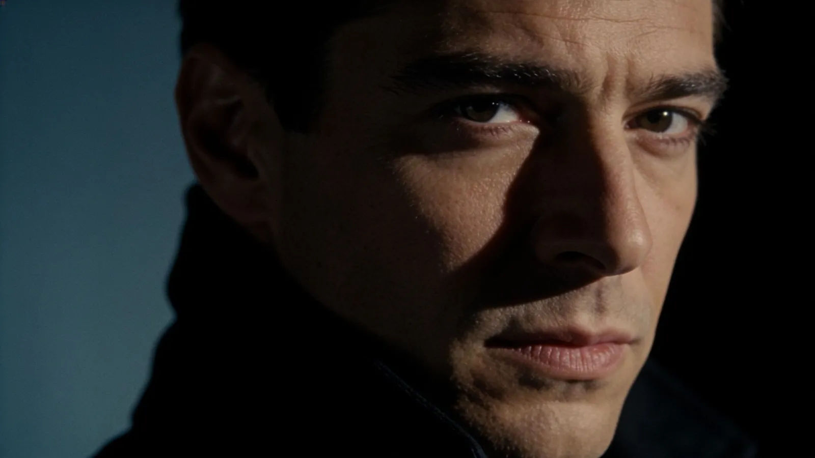 Composed man with commanding gaze in deep shadow