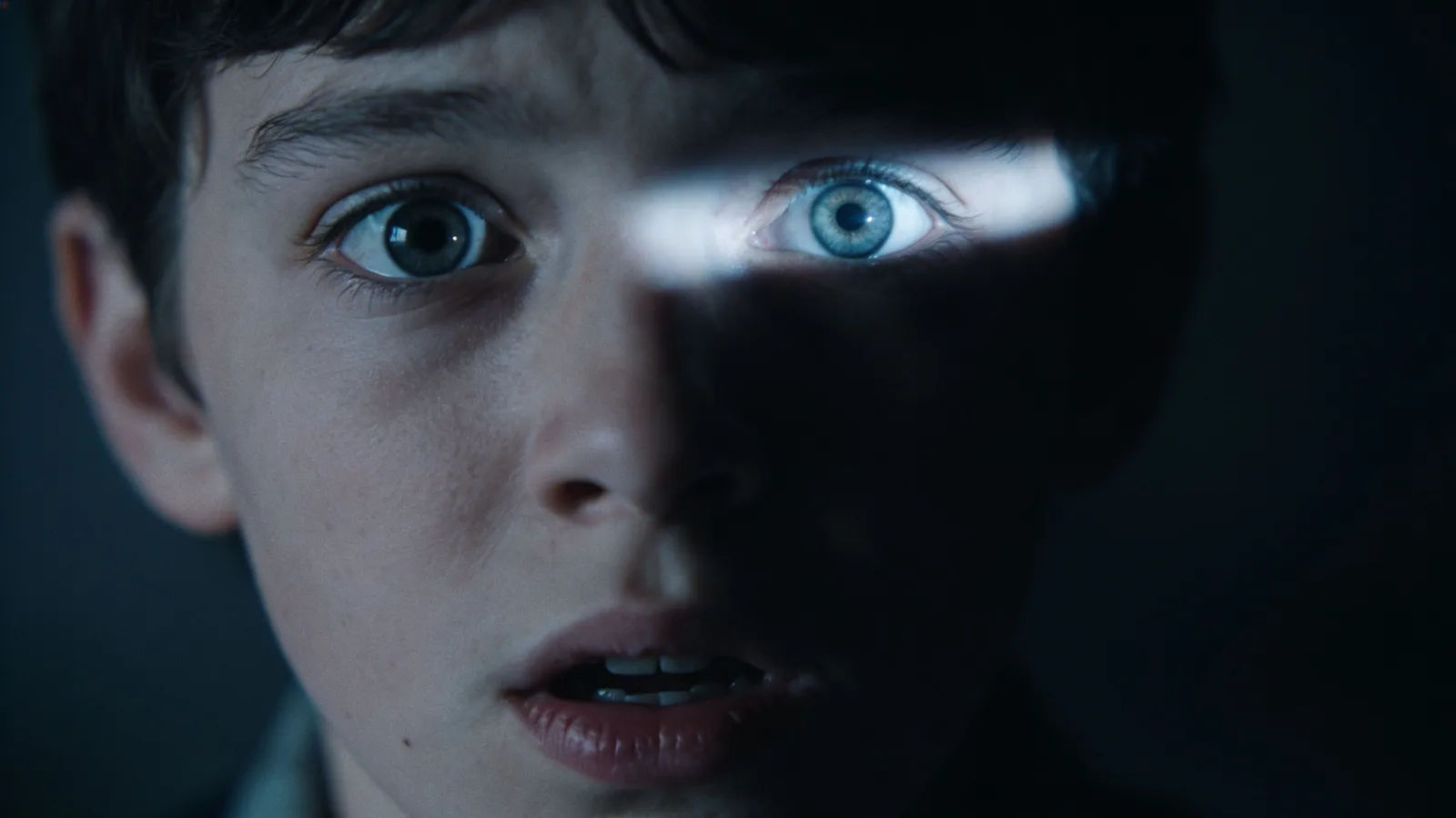 Frightened person with wide eyes in deep shadow