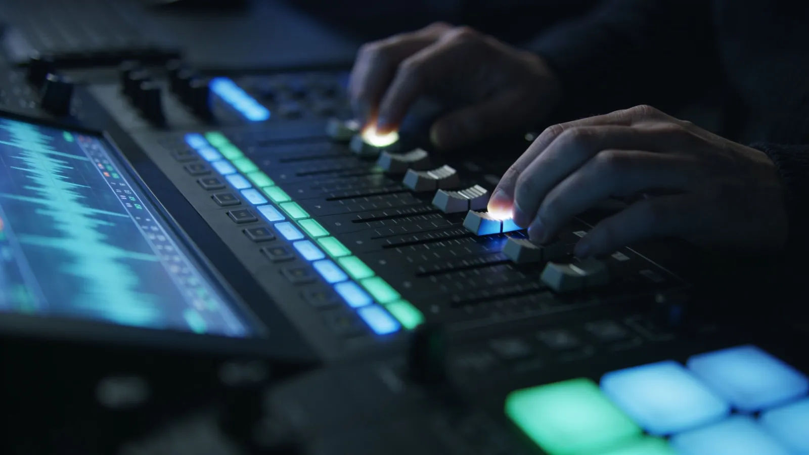 Hands at dark console with blue-green audio interface
