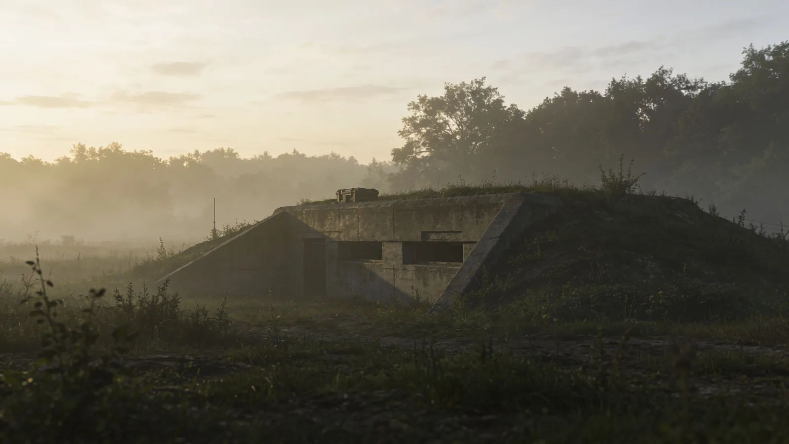 Misty tactical field with low bunker at dawn