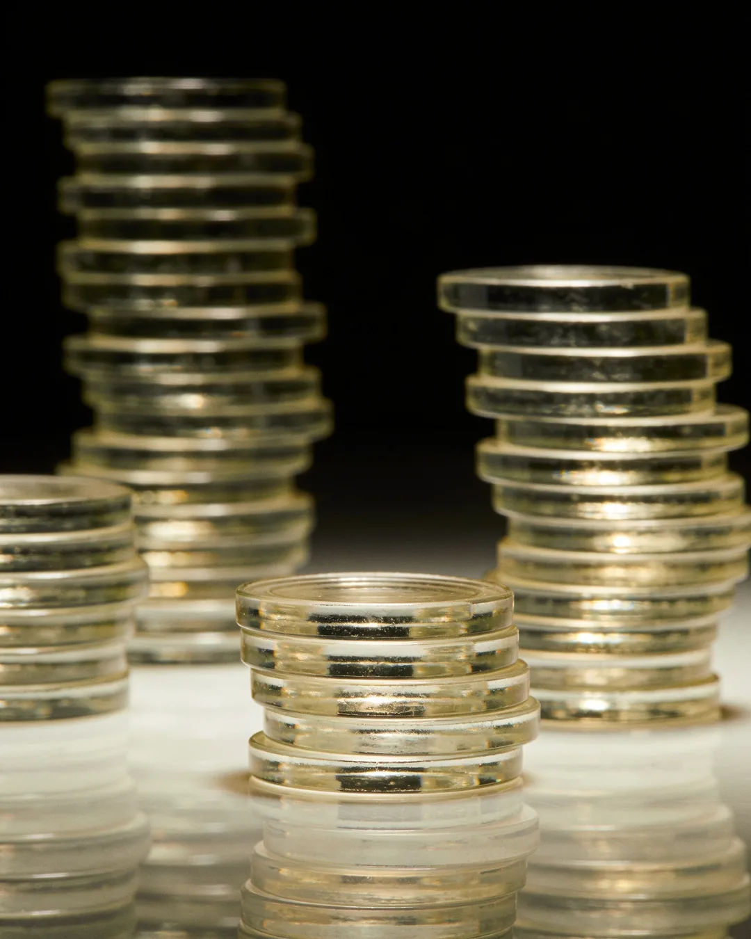 Stacks of glass tokens rising on a black ground