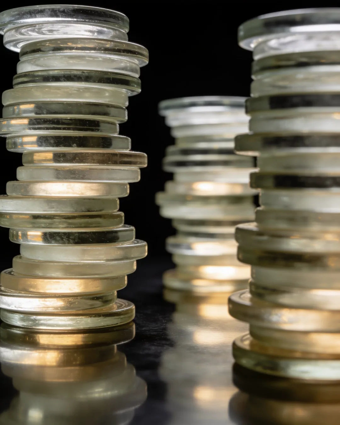 Stacks of glass tokens rising on a black ground