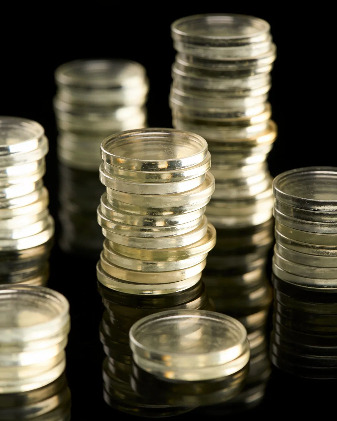 Stacks of glass tokens rising on a black ground