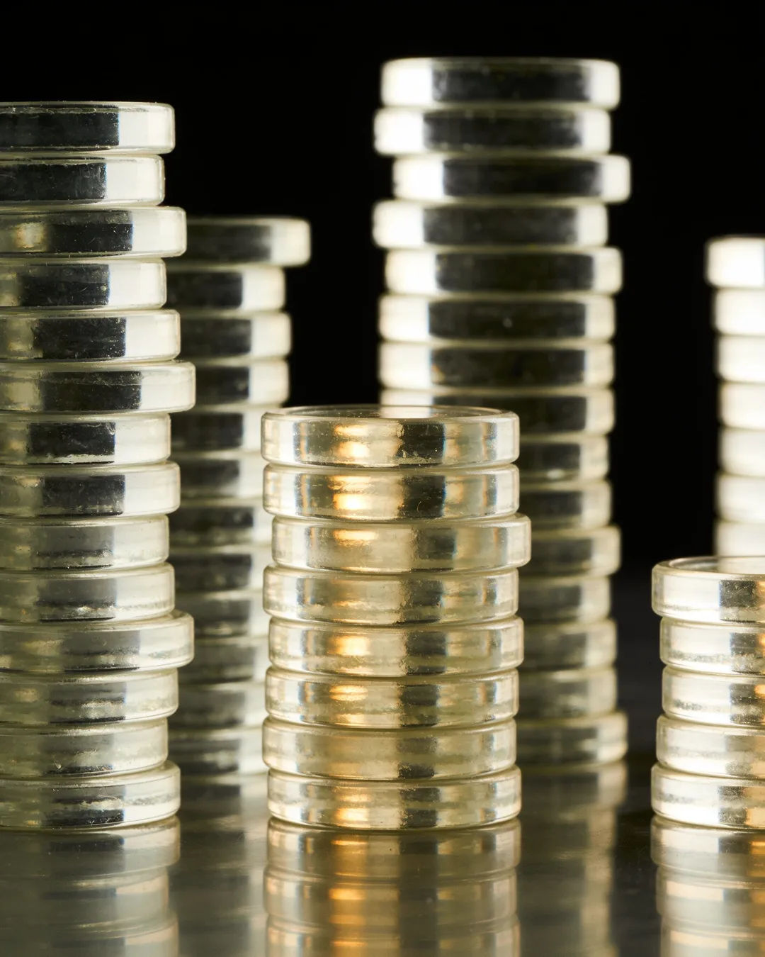 Stacks of glass tokens rising on a black ground