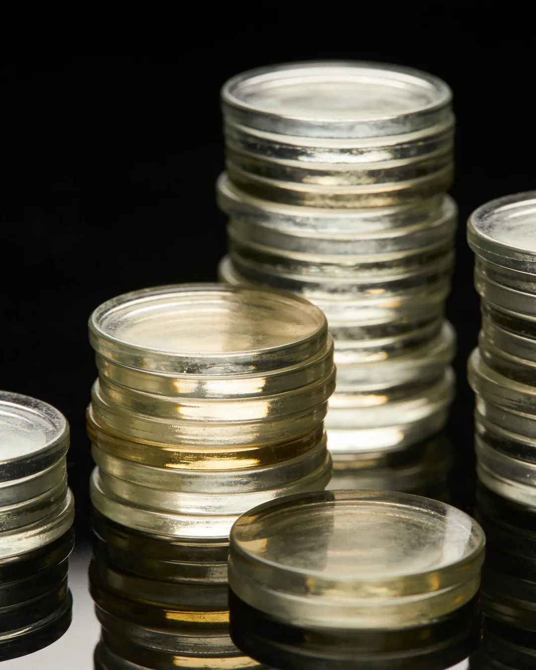 Stacks of glass tokens rising on a black ground