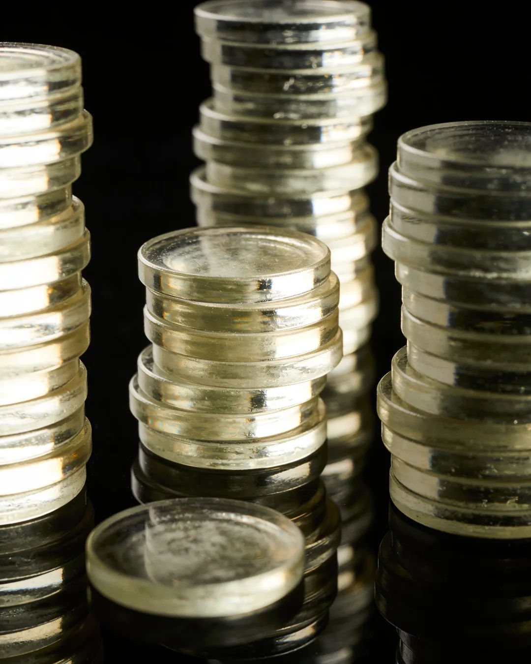 Stacks of glass tokens rising on a black ground