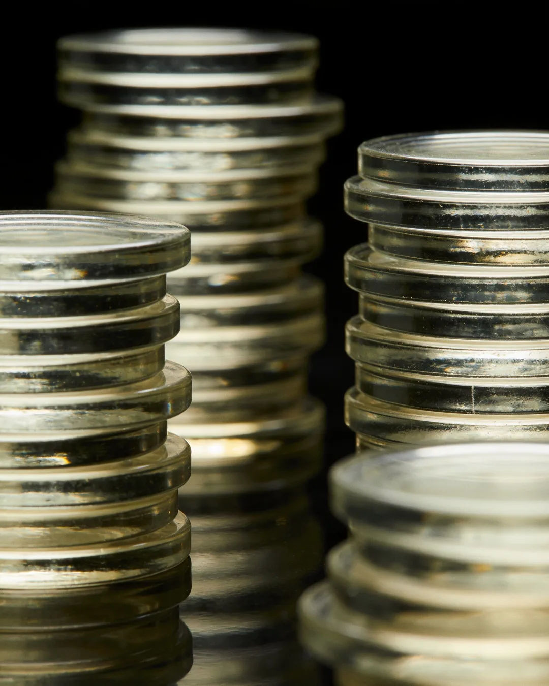 Stacks of glass tokens rising on a black ground