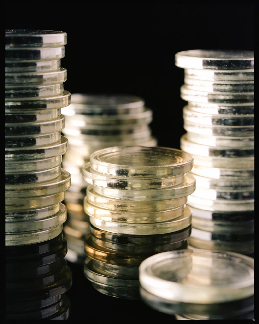 Stacks of glass tokens rising on a black ground