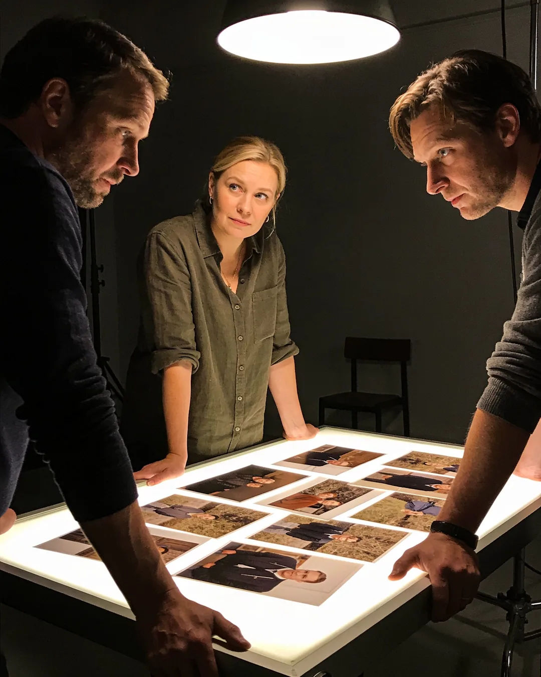 A Finnish production team reviewing printed frames on a lit table