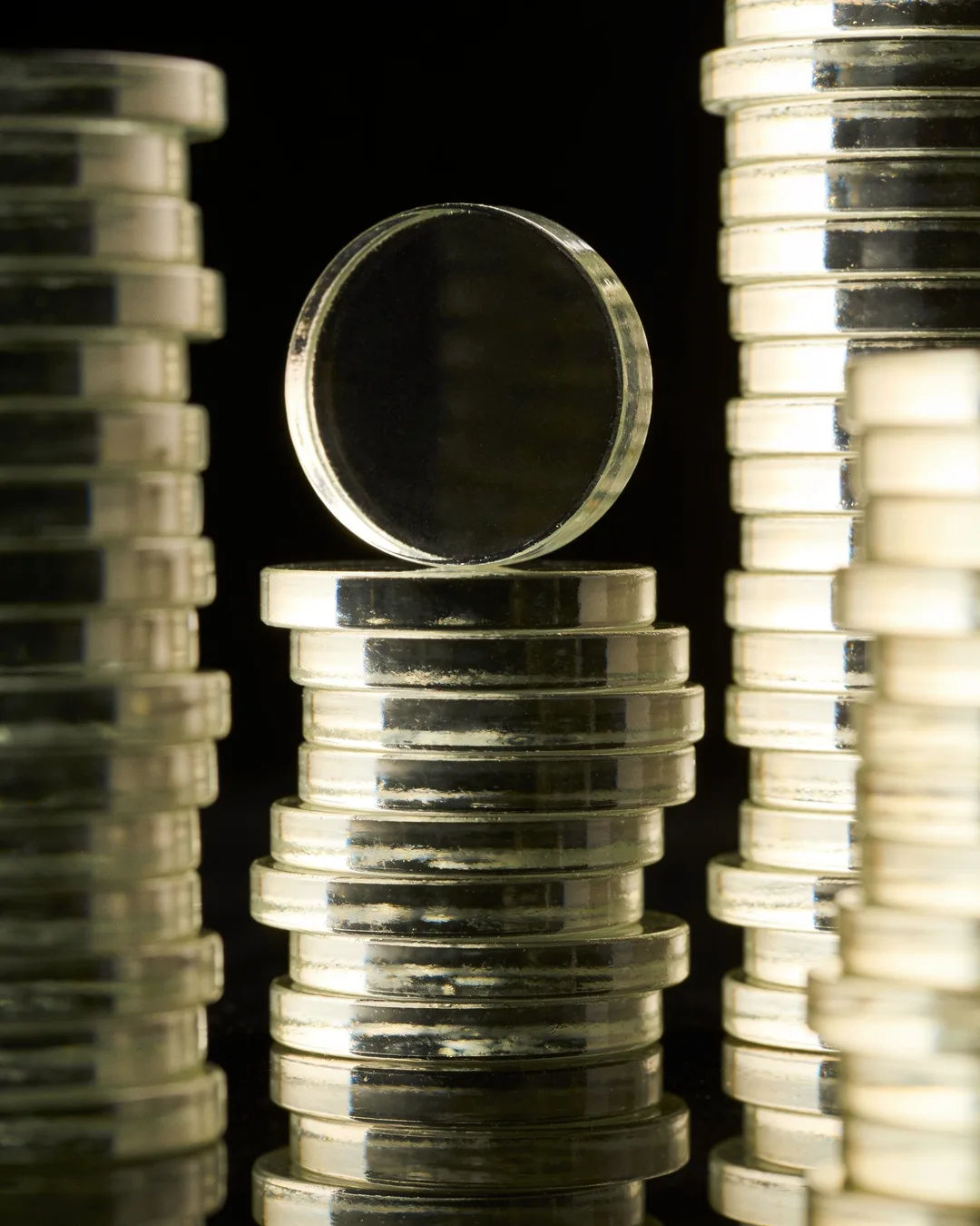 Stacks of glass tokens rising on a black ground