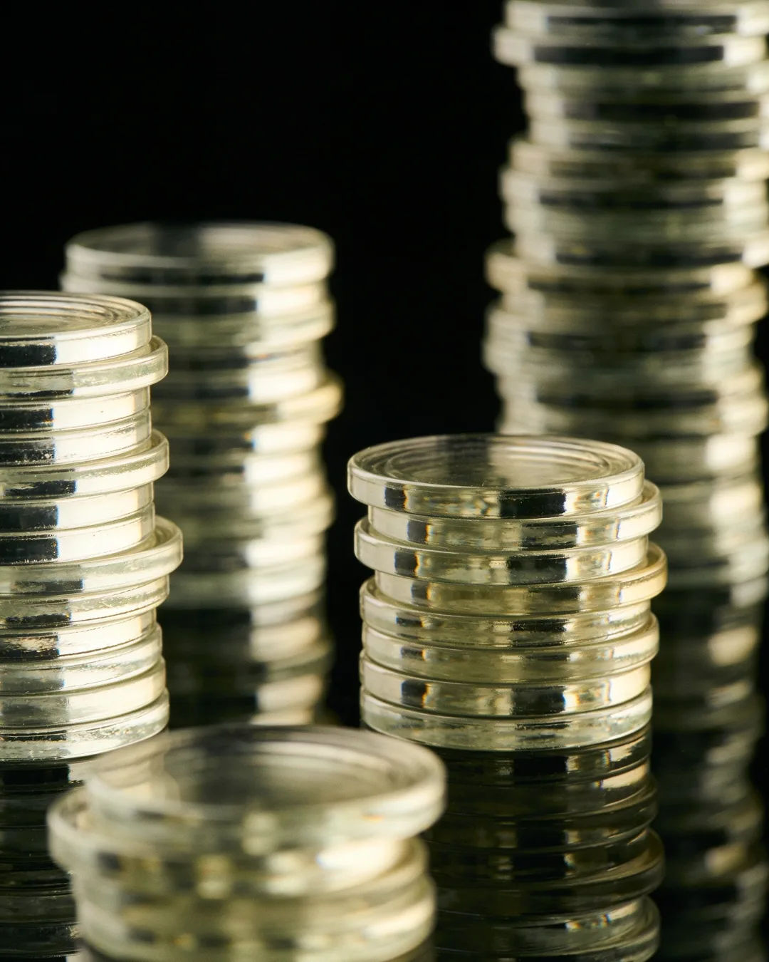 Stacks of glass tokens rising on a black ground