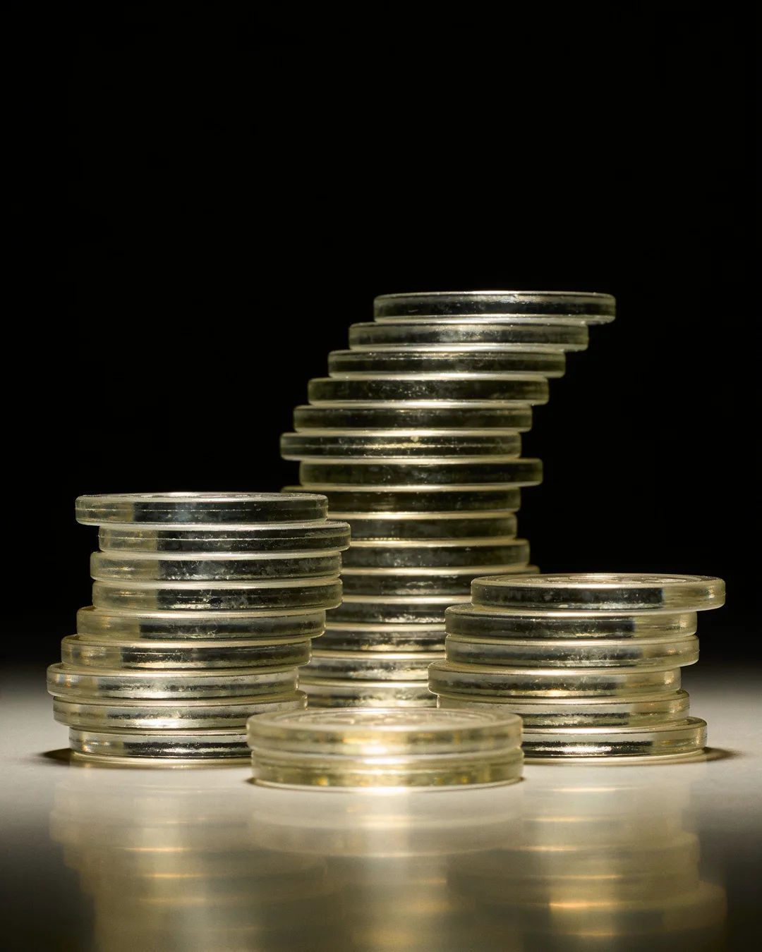 Stacks of glass tokens rising on a black ground